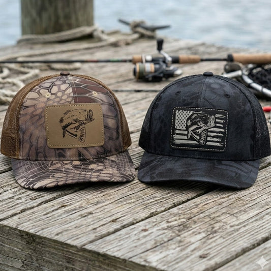 Two bass kryptek camo fishing hats with leather patches on a dock
