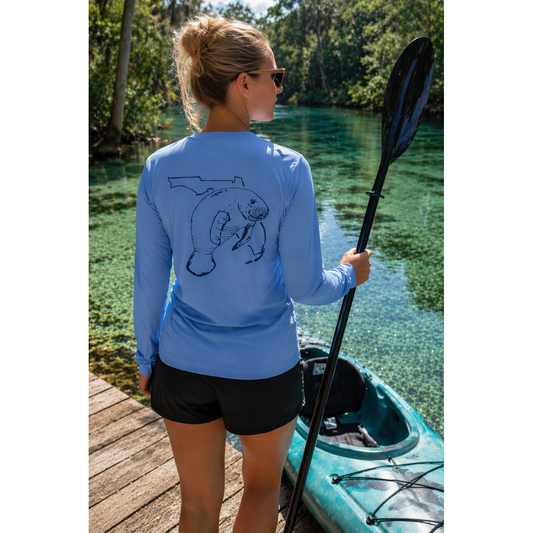 Woman wearing a light blue long sleeve UV sun shirt with a manatee design, getting ready to kayak on the Crystal River.