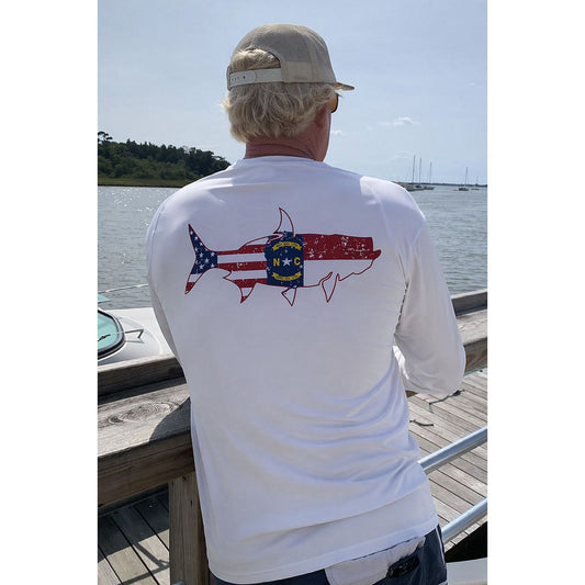 Man wearing a white long-sleeve UPF 50 performance sun shirt with a tarpon fish and State of North Carolina Flag graphic design on the back.