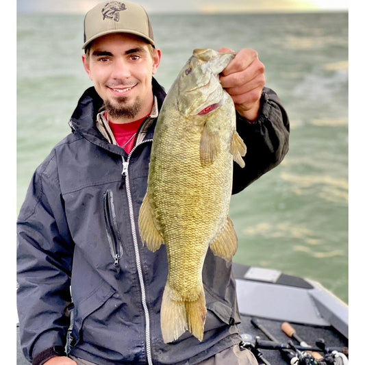 Model wearing black rain jacket with hood and Reel Fishy Tarpon embroidery