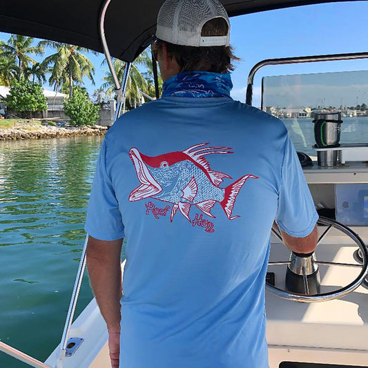 Model wearing light blue short sleeve shirt with hogfish graphic and 50+ UV protection by Reel Fishy Apparel.
