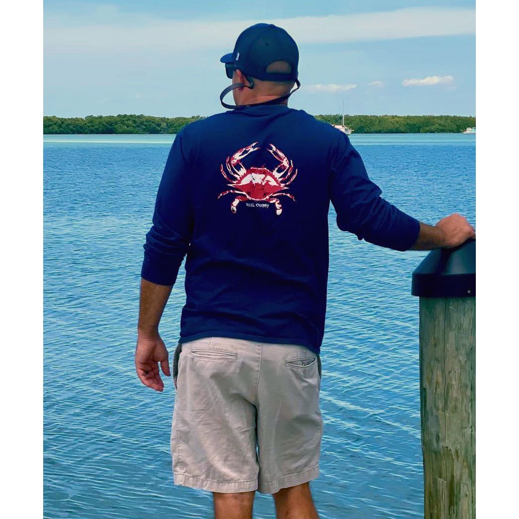 Model in navy long sleeve Reel Crabby performance shirt featuring blue crab design with 50+ UPF sun protection