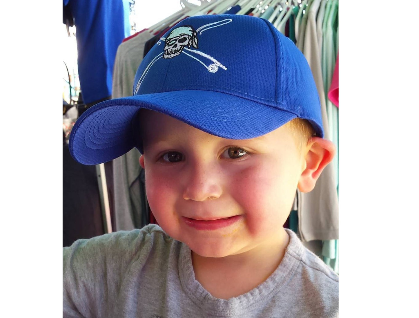 Youth wearing royal blue fishing hat with Reel Fishy Pirate Skull and Rods logo