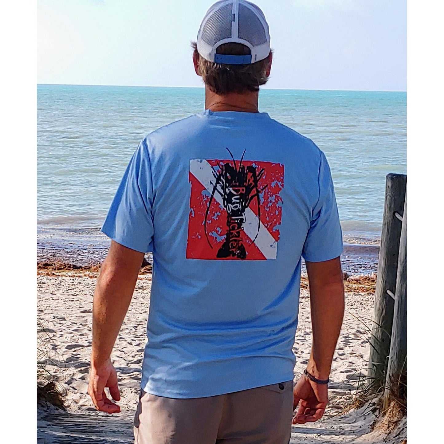 Model wearing Lobster Performance light blue short sleeve fishing shirt with 50+ UPF sun protection and "Bug Tickler" dive logo