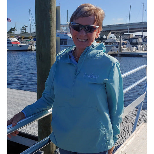 Model wearing Reel Fishy 1/2-Zip Pullover Windbreaker Jacket in Aqua Blue with Tarpon embroidery logo