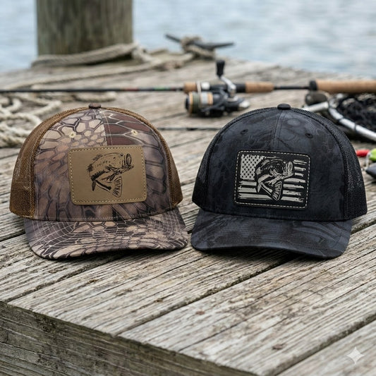 Two bass kryptek camo fishing hats with leather patches on a dock