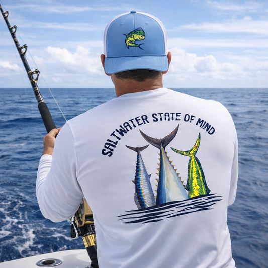 Fisherman wearing white long sleeve performance UV shirt with Offshore Slam fish tails (wahoo, tuna, mahi) and text 'Saltwater State of Mind' and mahi trucker hat while fishing offshore.

