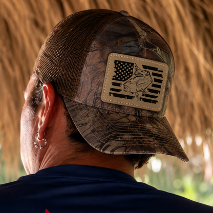 Model wearing a camo trucker fishing hat with redfish American flag patch and navy UPF 50 performance fishing shirt