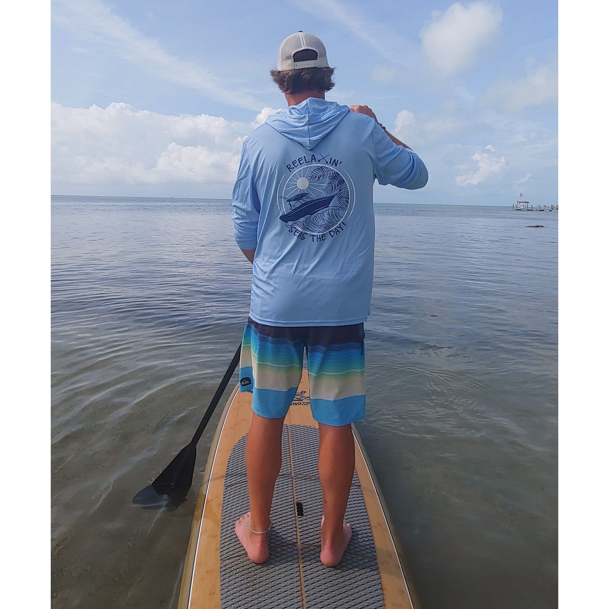 Model wearing light blue Reelaxin' Seas the Day dri-fit 50+ sun protection long sleeve hoodie