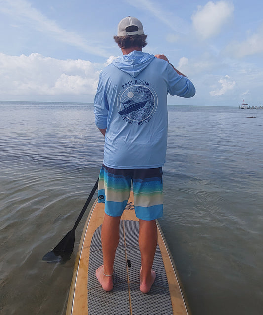 Model wearing light blue Reelaxin' Seas the Day dri-fit 50+ sun protection long sleeve hoodie