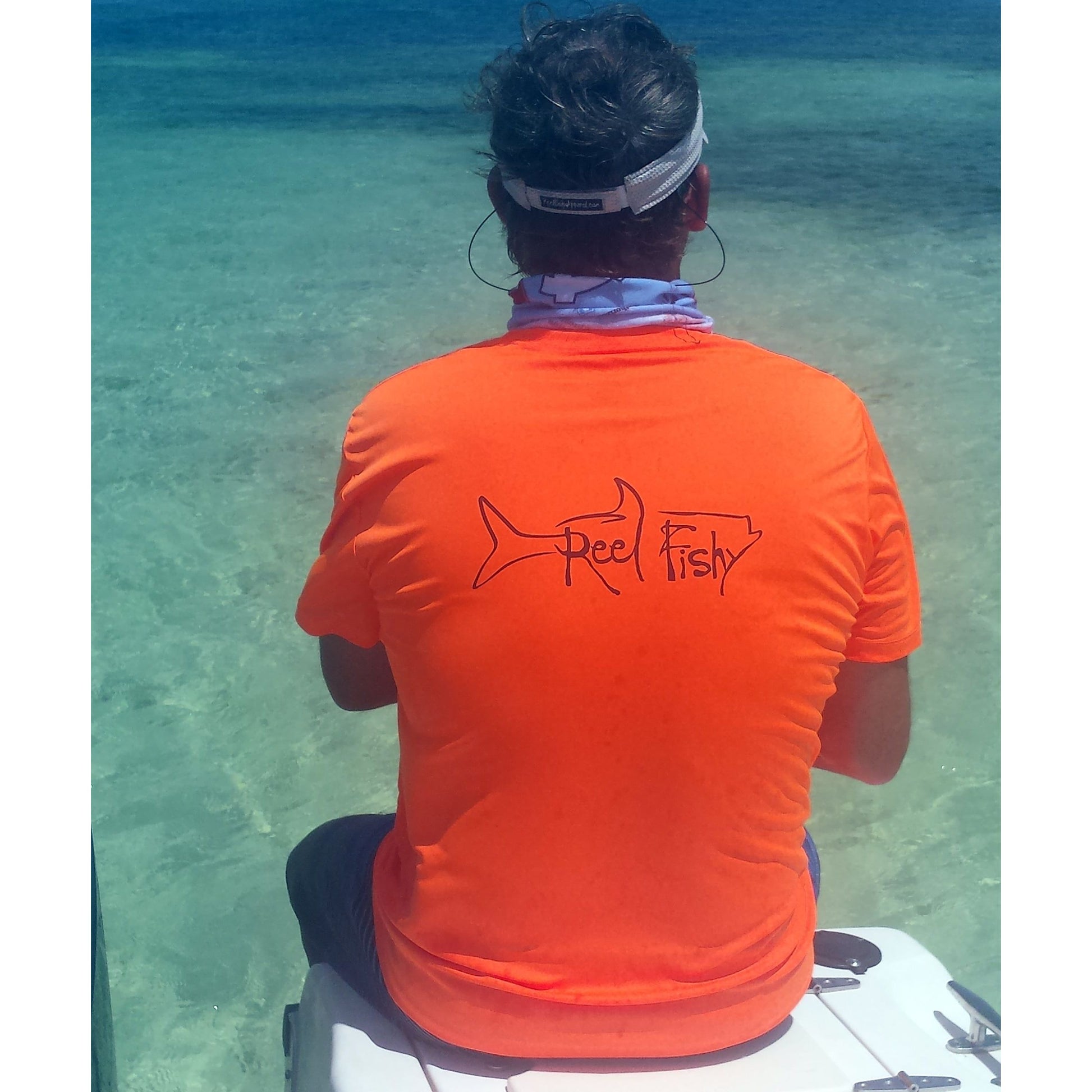 Model wearing neon orange performance dry-fit short sleeve sun shirt with Reel Fishy tarpon design.