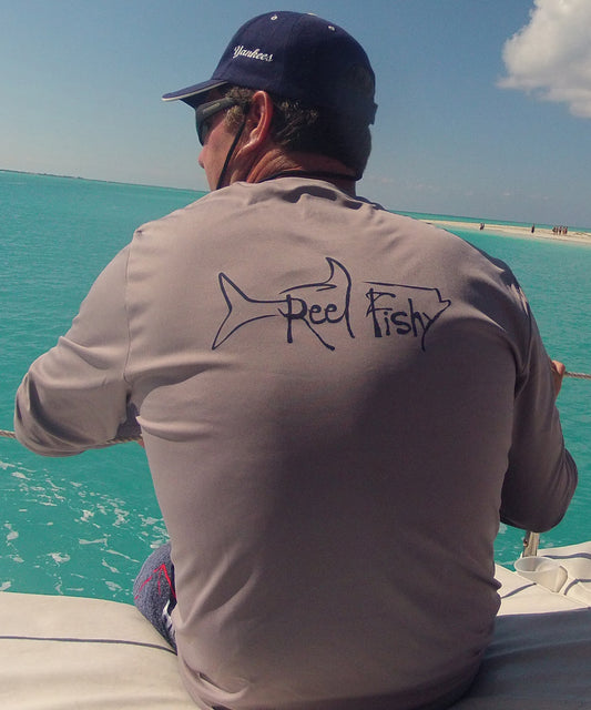 Model wearing a gray long sleeve Reel Fishy Tarpon Fishing Dri-Fit shirt with 50+UPF sun protection.