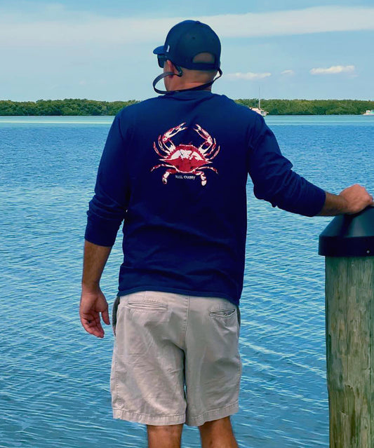 Model in navy long sleeve Reel Crabby performance shirt featuring blue crab design with 50+ UPF sun protection