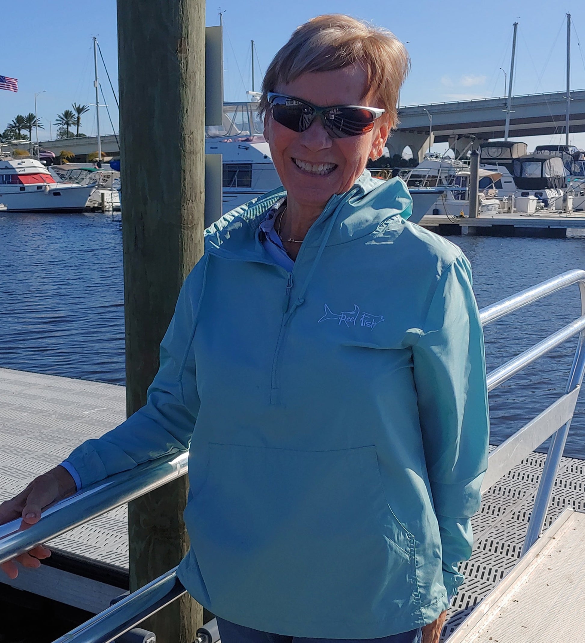 Model wearing Reel Fishy 1/2-Zip Pullover Windbreaker Jacket in Aqua Blue with Tarpon embroidery logo